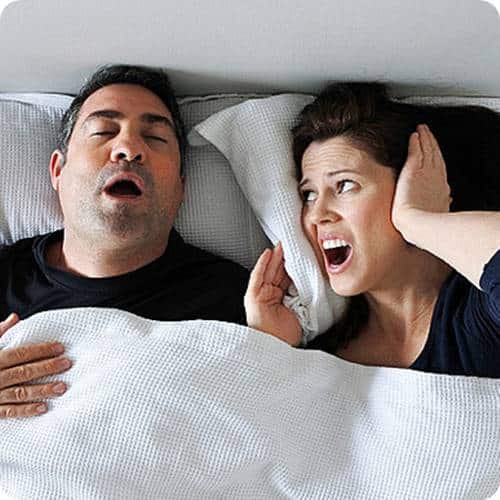 a man and woman lying in bed with their mouth open